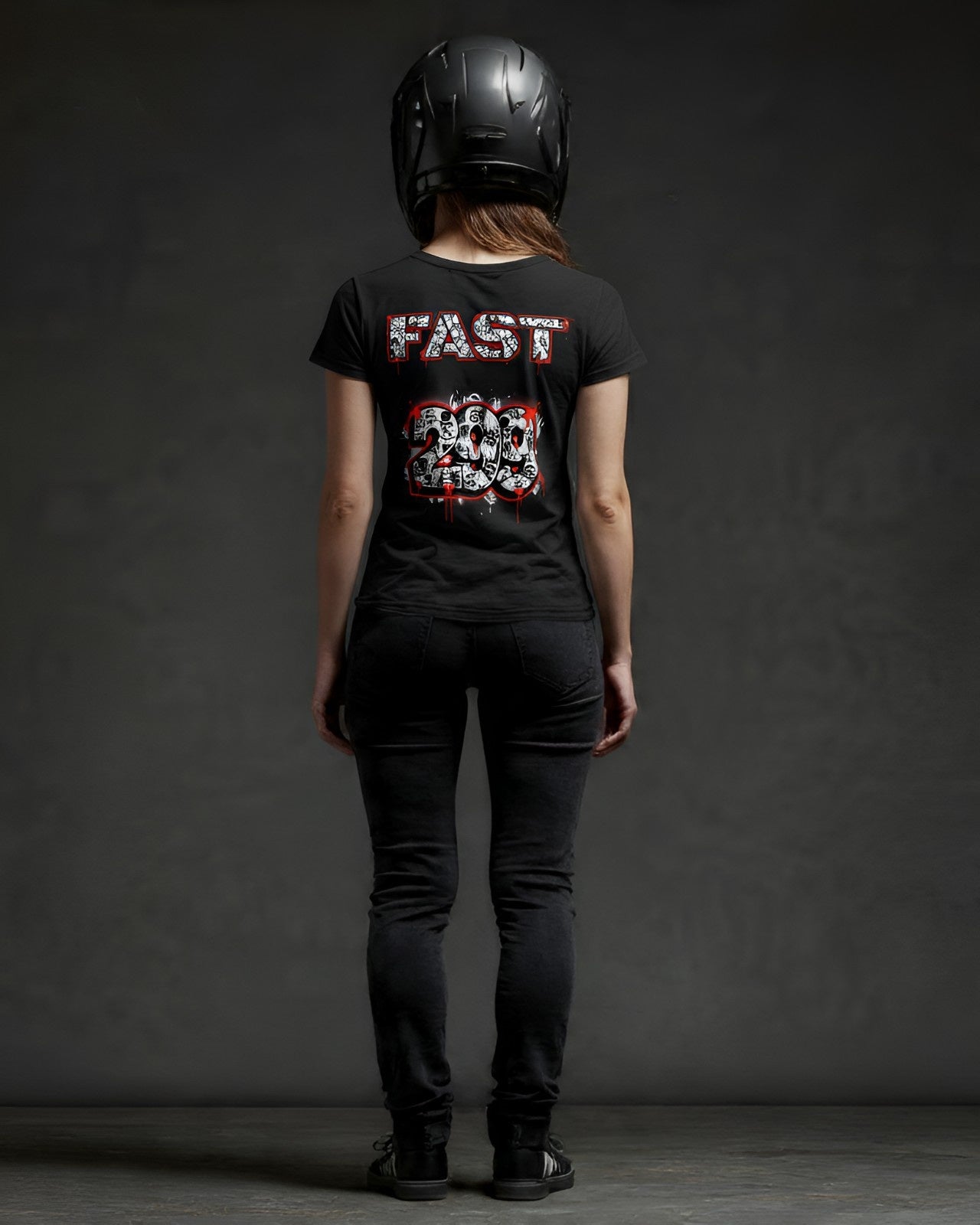 A woman from behind, wearing a black superbike t-shirt with "FAST 299" and a motorcycle enthusiast art shirt design in red and white, black jeans, and a helmet. The logos have Alec Monopoly inspiration.
