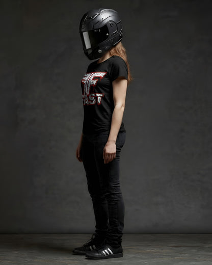 Woman in black jeans, adidas, and a superbike t-shirt, wearing a black motorcycle helmet. This motorcycle enthusiast apparel art shirt features a red and white graphic inspired by Alec M.