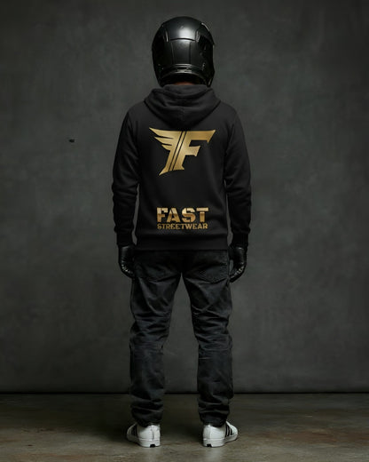 Person wearing a black t-shirt with gold 'FAST' and winged 'F' design, black helmet, and black pants on a dark background