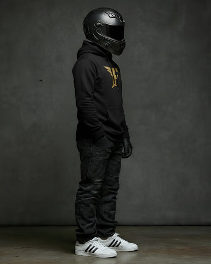 Person wearing a black helmet, black hoodie with a gold 'F' logo, black pants, and white sneakers on a gray background