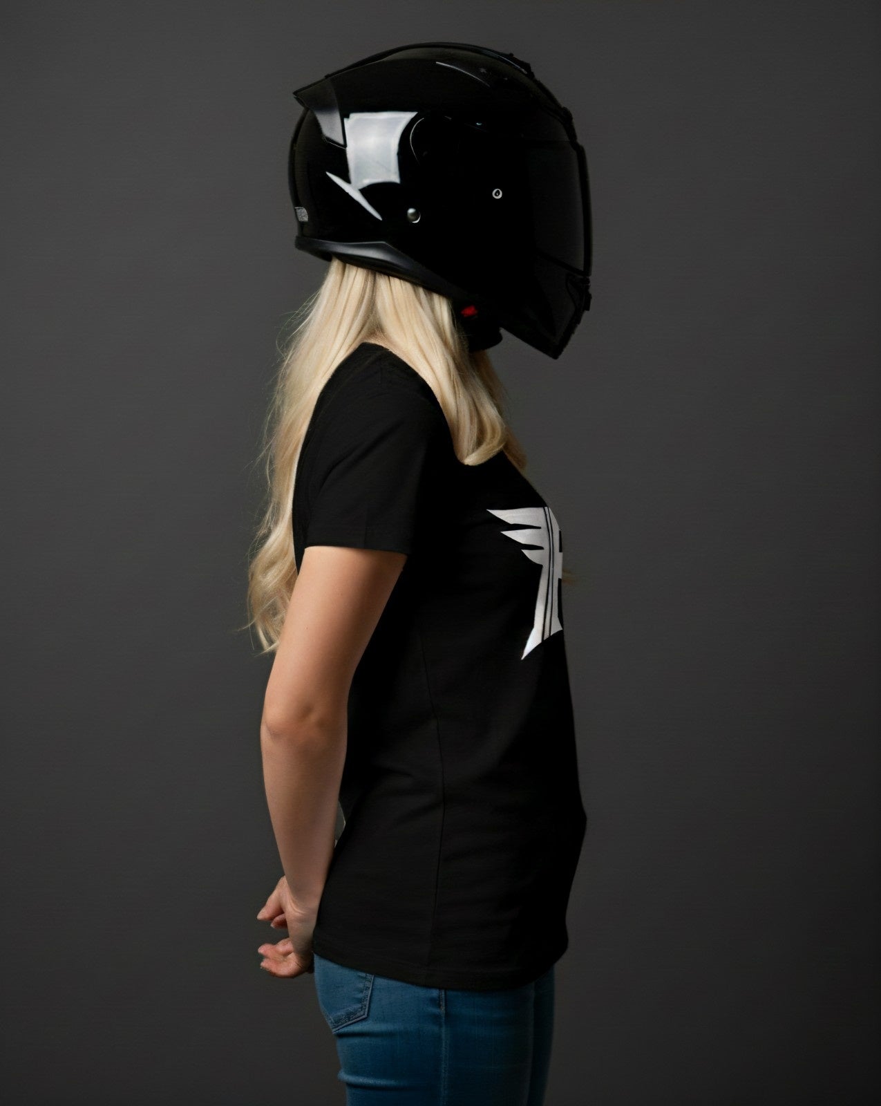 Person wearing a black helmet and black t-shirt with a white design on a dark background