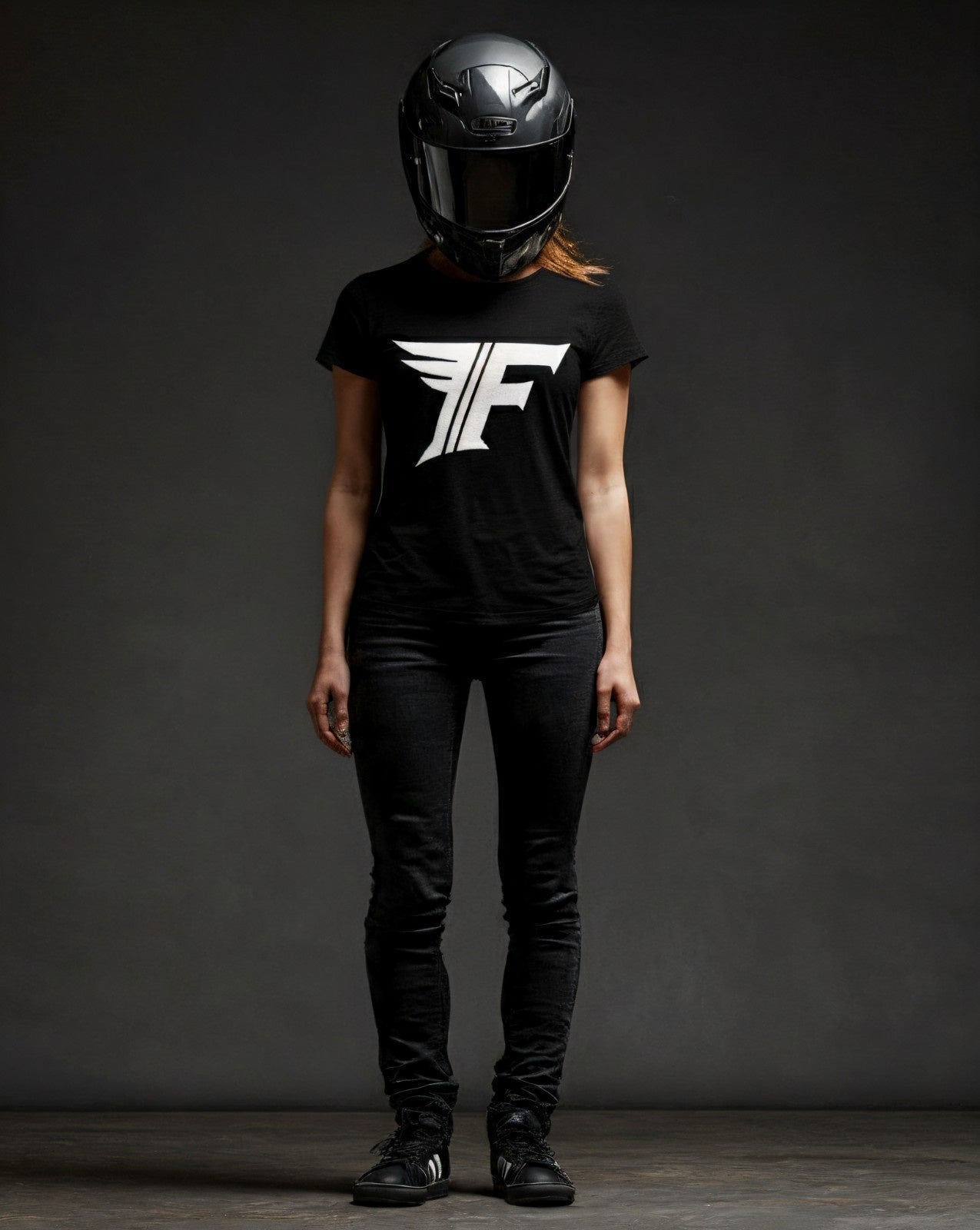 Person wearing a black t-shirt with a white logo and a black helmet on a dark background