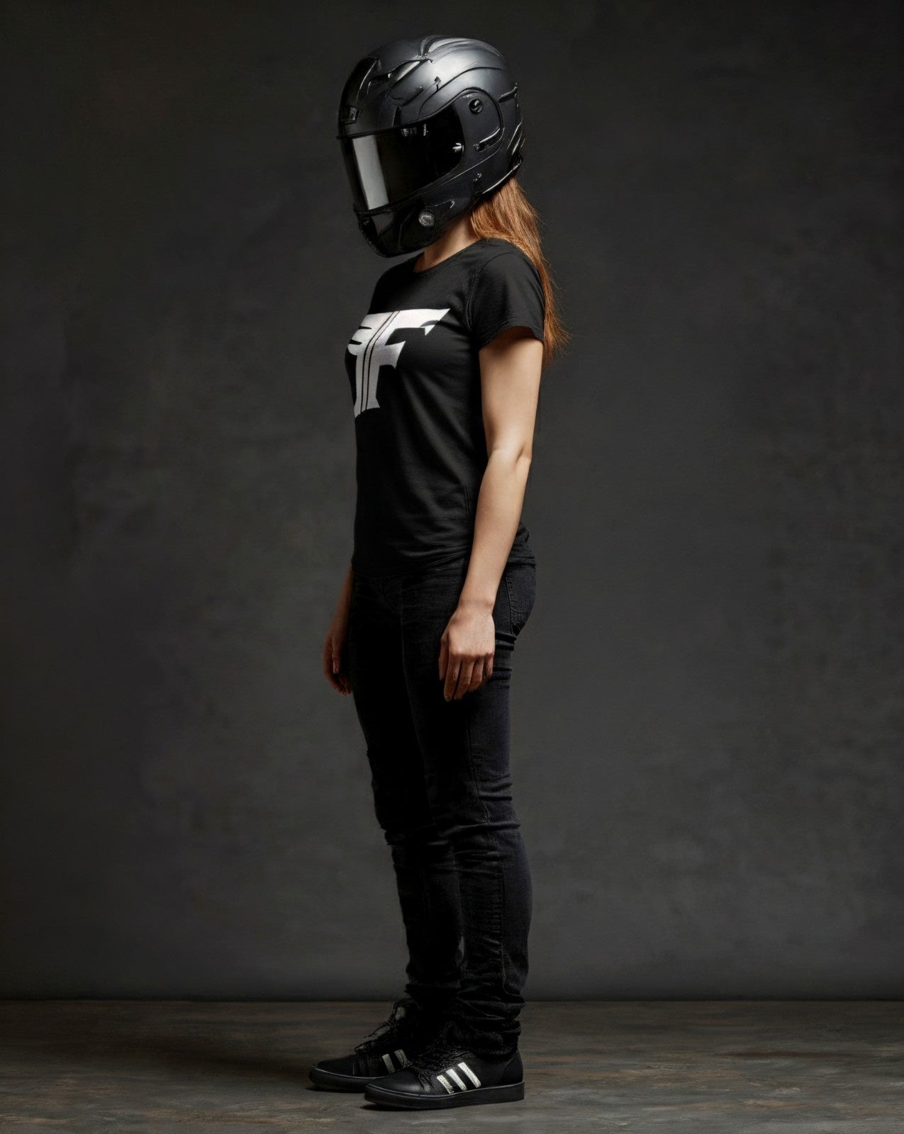 Person wearing a black helmet and black t-shirt with a logo on a dark background