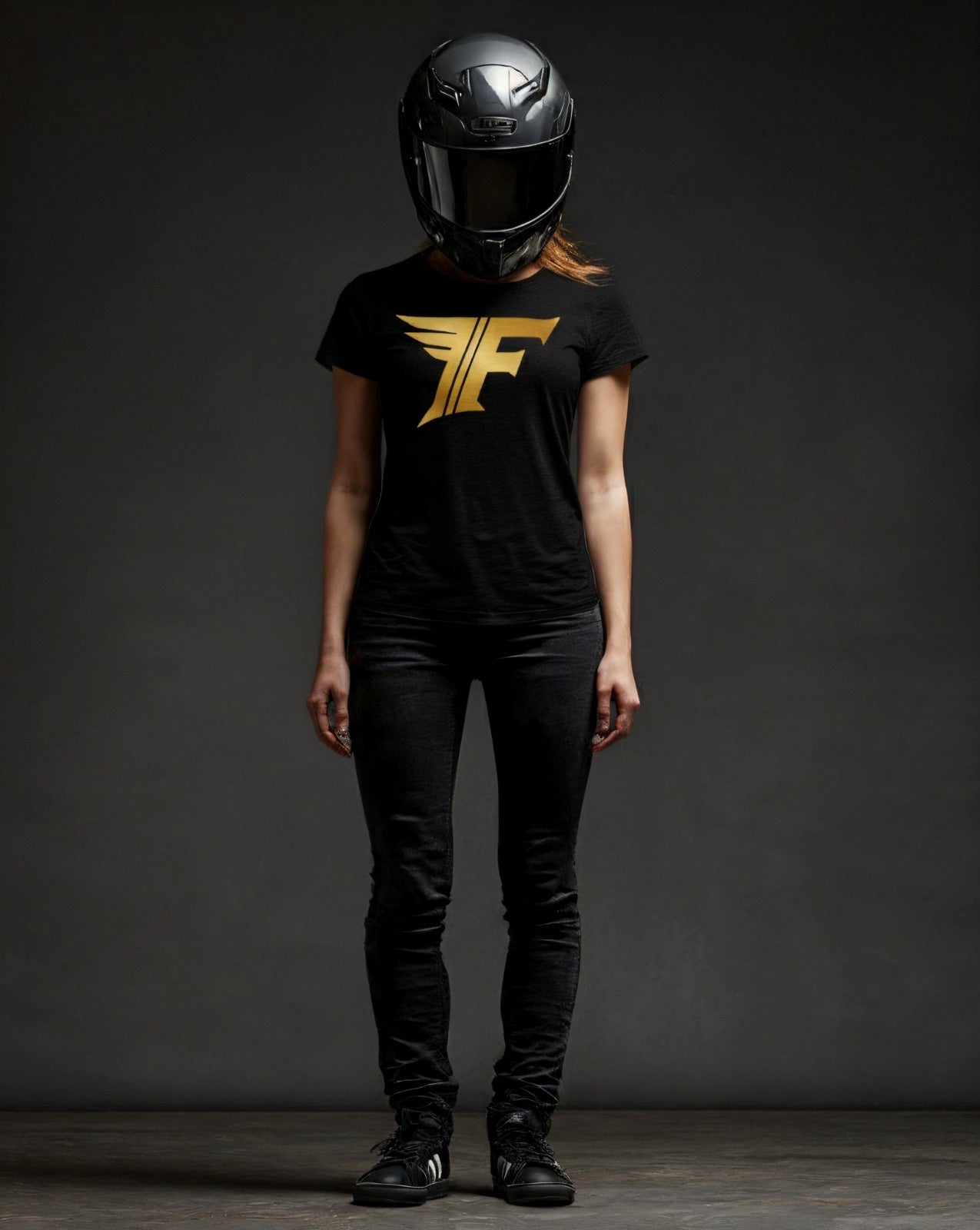 Person wearing a black t-shirt with a gold logo and a black helmet on a dark background