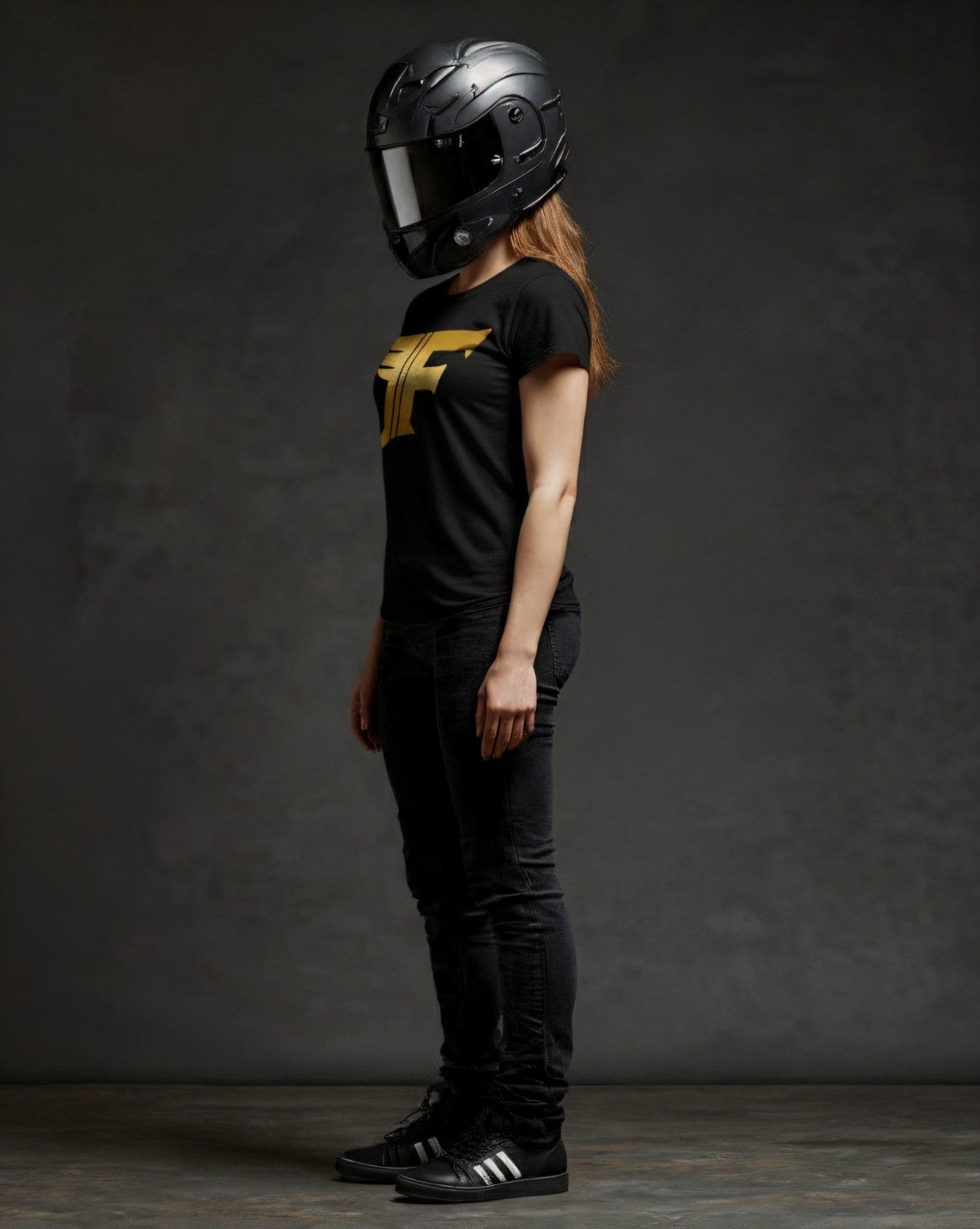Person wearing a black helmet and black t-shirt with a yellow logo against a dark background
