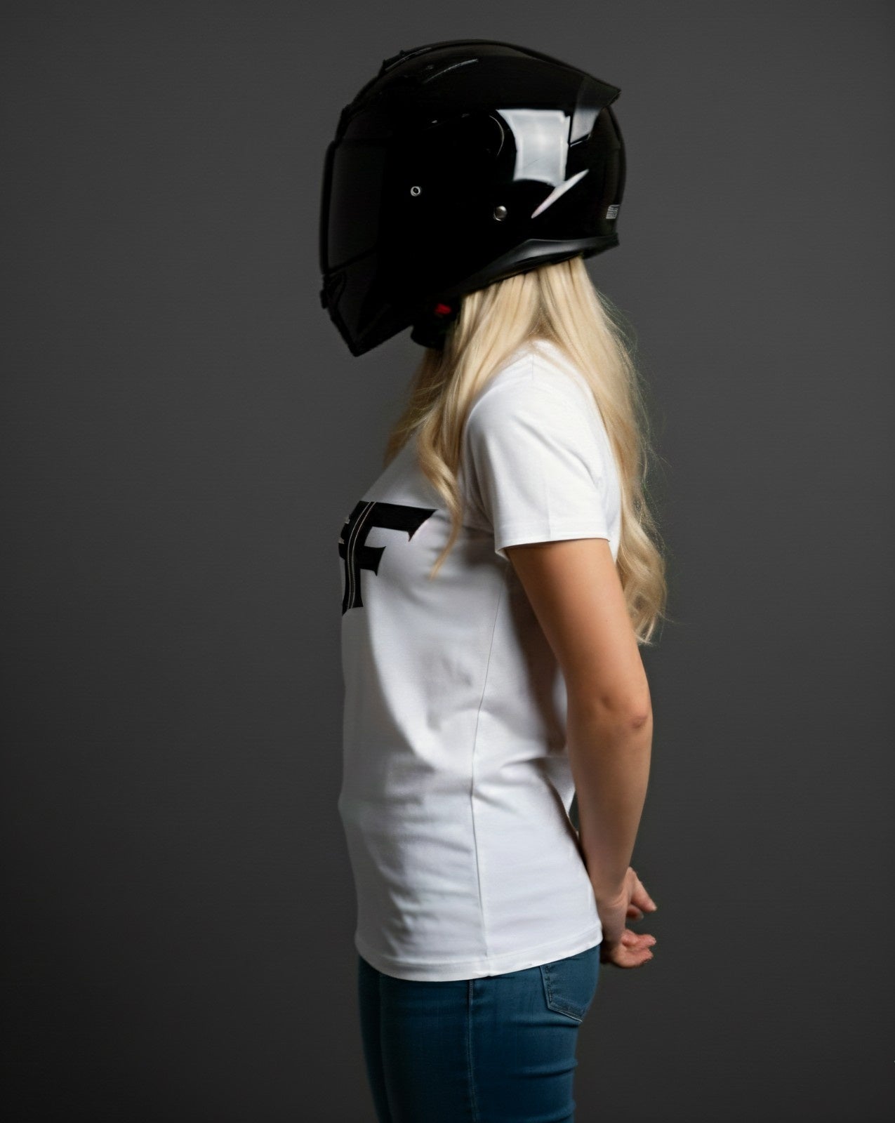 Person wearing a black helmet and black t-shirt with a logo on a dark background