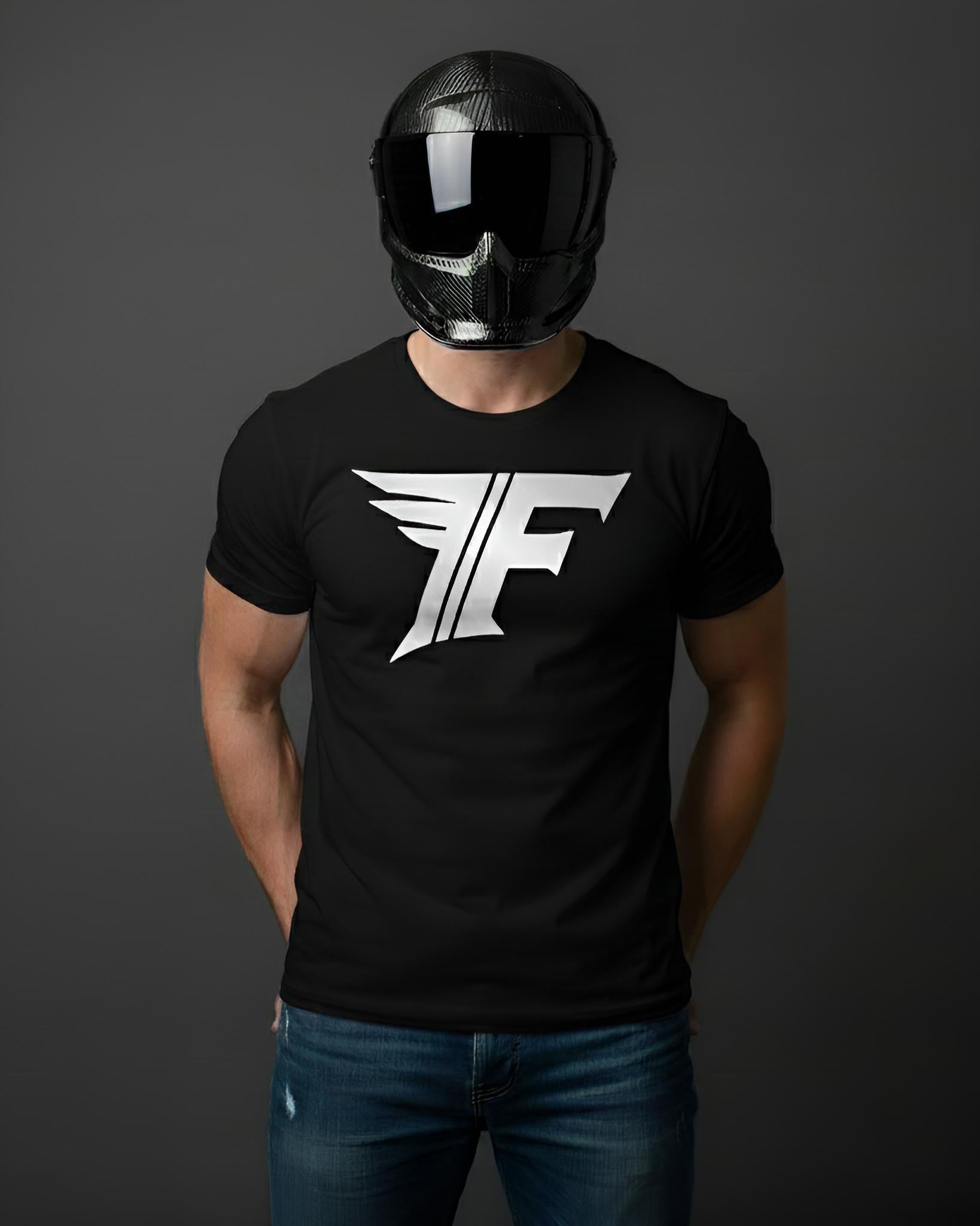 Person wearing a black t-shirt with a white logo and a black helmet on a dark background
