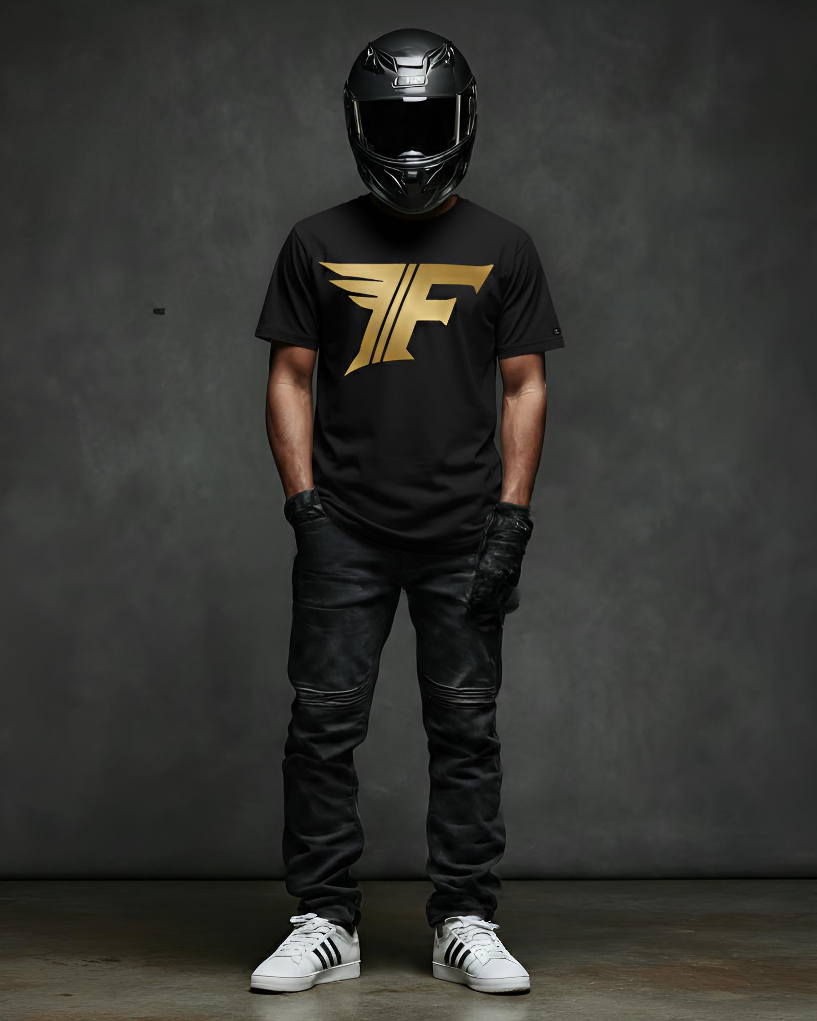 A man wearing a black shirt featuring a gold "F" logo with wings, black jeans, motorcycle gloves, a helmet, and white sneakers.