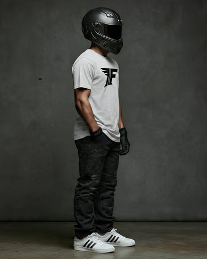 Person wearing a white t-shirt with a logo, black helmet, and dark pants against a gray background