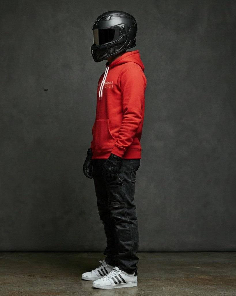 A man wearing a red Fast Streetwear cursive logo hoodie shirt with a Helmet (Racing), White Adidas superstars, and bkack jeans