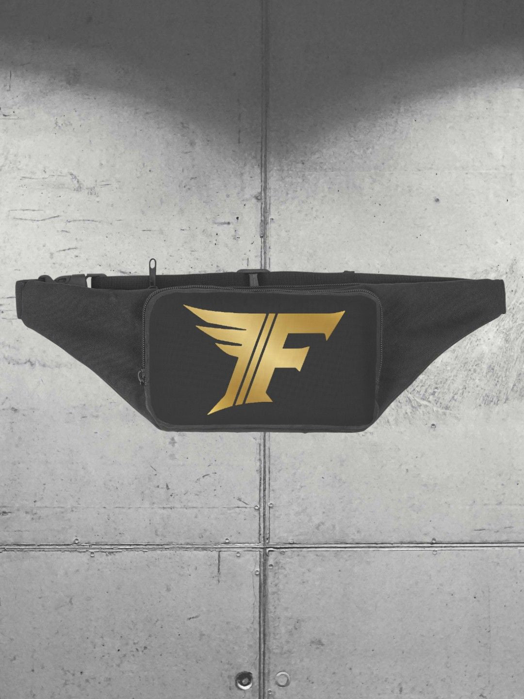 Black waist bag (fanny pack) displayed flat against a grey metal panel background, featuring a bold gold winged 'F' logo on the front.