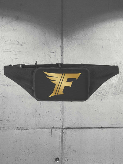 Black waist bag (fanny pack) displayed flat against a grey metal panel background, featuring a bold gold winged 'F' logo on the front.