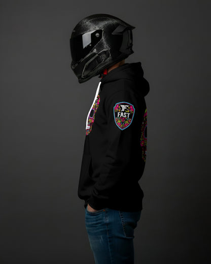 Side view of black hoodie showing the colorful shield "FAST" logo patch on the left shoulder. Model wears a black motorcycle helmet.