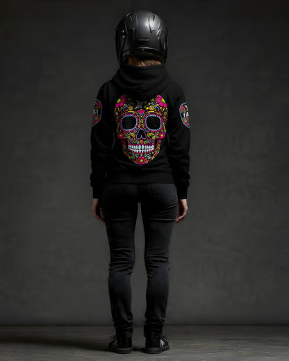 Back view of a black hoodie with large, colorful sugar skull design, worn by a figure in a motorcycle helmet. Shows sleeve patches and dark jeans.