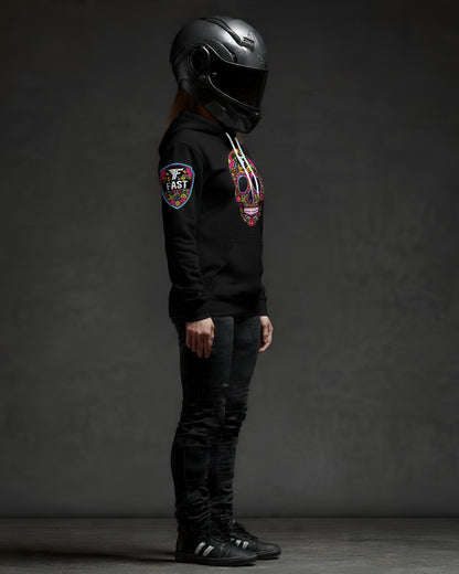 Right side profile of a black hoodie with a sugar skull design and a prominent sleeve patch, worn by a figure in a full-face motorcycle helmet.