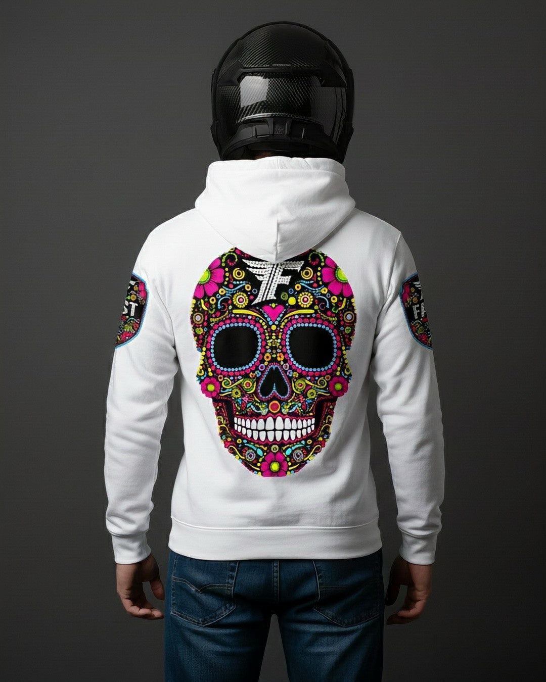 Back view of the white hoodie featuring a large, brightly colored Day of the Dead sugar skull design. Worn by a person in a carbon fiber motorcycle helmet.
