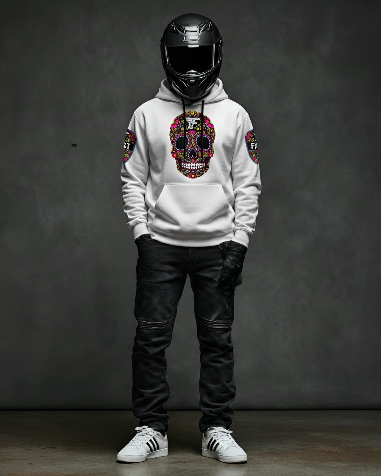 Front view of a white pullover hoodie featuring a vibrant Day of the Dead sugar skull graphic, modeled with a motorcycle helmet.