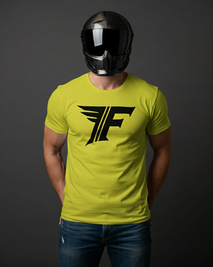 A man in a carbon fiber motorcycle helmet wears a bright yellow t-shirt with a large black logo: a stylized "F" with wings/stripes.
