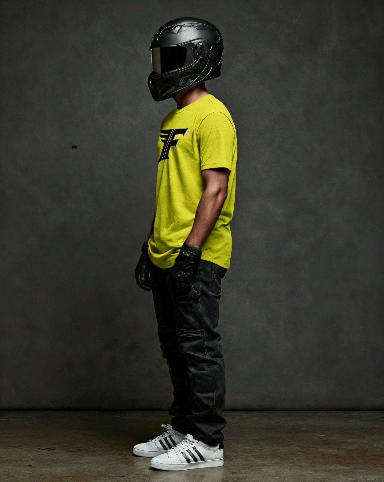 Profile shot of a man wearing the casual fit Neon Yellow FF Logo T-shirt with black gloves, black helmet, and dark denim pants.