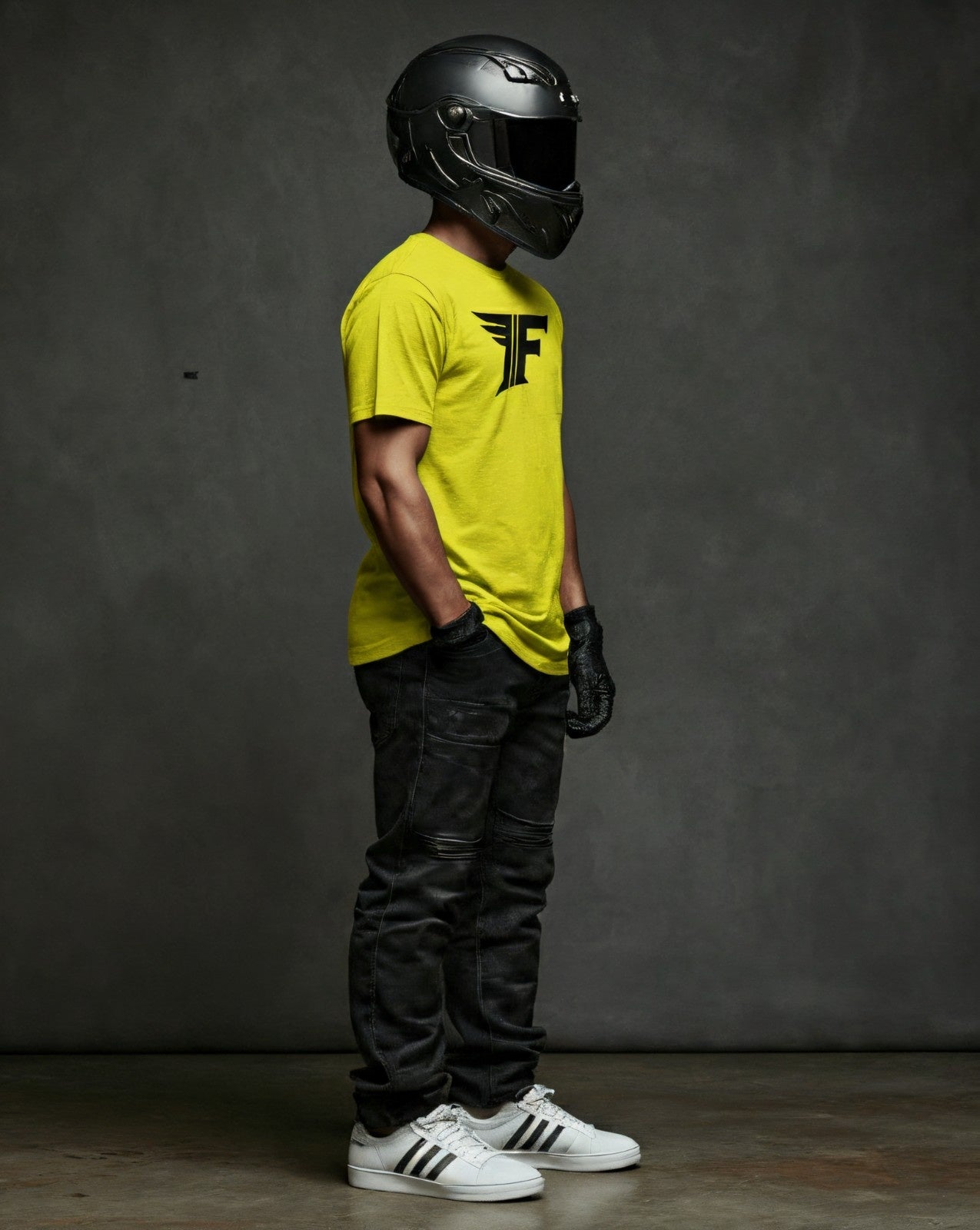 Bright yellow crew-neck t-shirt with a black "F" logo, modeled by a person wearing a helmet, gloves, and jeans in a side view.
